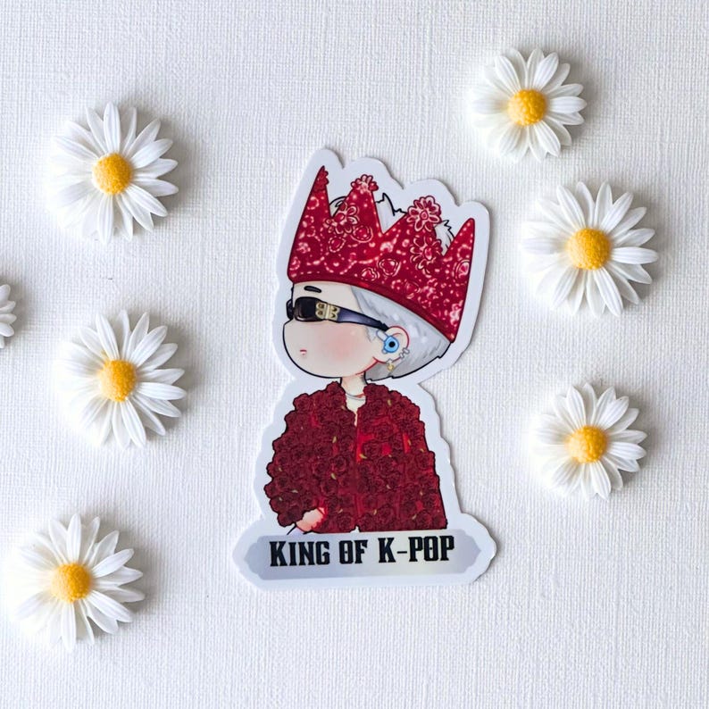 Puede incluir: Una pegatina con una figura de dibujos animados con una corona roja y una chaqueta roja cubierta de rosas, con gafas de sol. El texto "KING OF K-POP" est&aacute; en la parte inferior. Las margaritas blancas con centros amarillos rodean la pegatina.