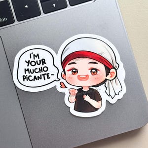 Puede incluir: Una pegatina con un personaje de dibujos animados con un gorro blanco y una cinta roja en la cabeza. El personaje sonríe y tiene un bocadillo que dice "I'M YOUR MUCHO PICANTE~". Un pequeño corazón rosa está al lado del personaje.