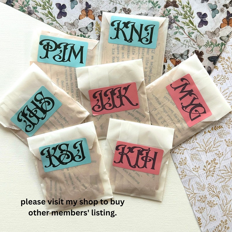 May include: Eight small white paper envelopes with different colored labels. Each label has a different three-letter monogram in black. The monograms are: PIM, KNI, JIK, MYG, IJS, KSI, and KIH. The text "please visit my shop to buy other members' listing." is printed below the envelopes.