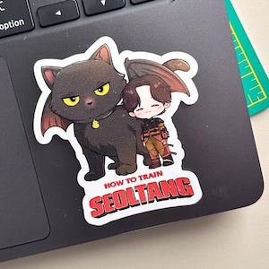 May include: A sticker featuring a black cat with bat-like wings and a small character. The cat has yellow eyes and a gold collar. The text "HOW TO TRAIN SEOLTANG" is in red and white.