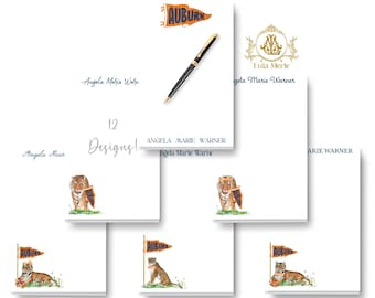 May include: A collection of white rectangular notepads featuring various personalized designs, including tiger illustrations, an Auburn pennant, a gold crest with the text Lula Merle, and the name Angela Marie Warner printed in blue and black ink.