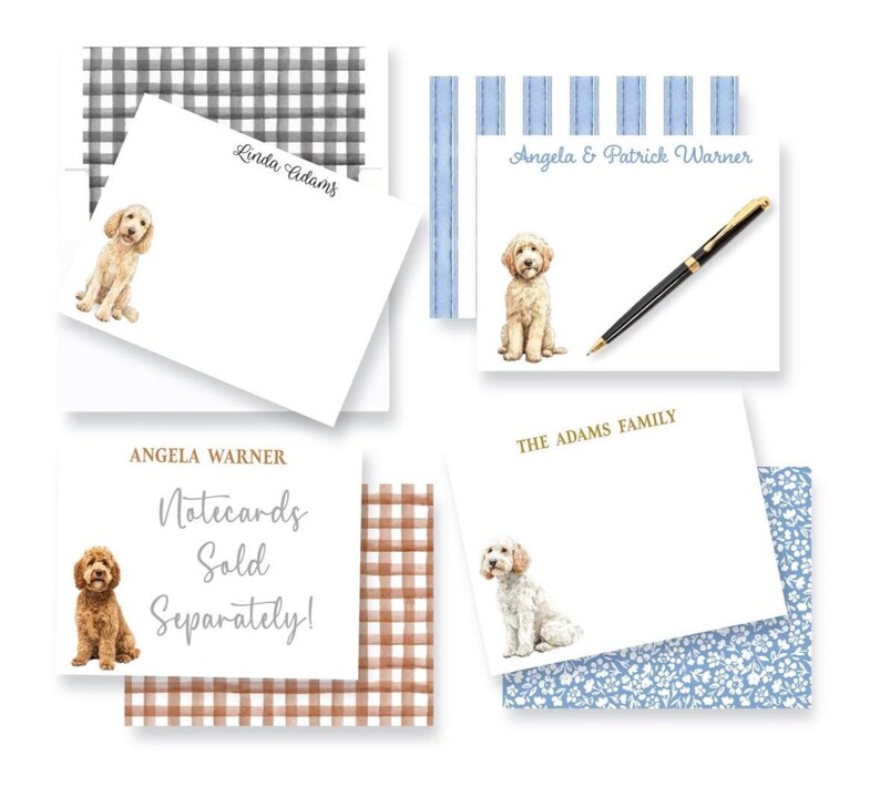 May include: A collection of rectangular white notecards featuring watercolor illustrations of golden-colored dogs. The cards display various names and text including Linda Adams, Angela & Patrick Warner, Angela Warner, The Adams Family, and Notecards Sold Separately. A black pen rests on one card, and several cards are paired with patterned envelopes in black gingham, blue stripes, brown gingham, and blue floral prints.