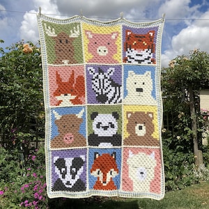Könnte beinhalten: Eine gehäkelte Babydecke mit einem bunten Patchwork-Muster, das verschiedene Tiergesichter zeigt, darunter ein Reh, ein Schwein, ein Tiger, ein Zebra, ein Eisbär, eine Kuh, ein Panda, ein Bär, ein Dachs, ein Fuchs und ein Lama.