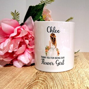 May include: White ceramic mug with the name "Chloe" and the text "Thank you for being our Flower Girl". A flower girl illustration is featured on the mug.