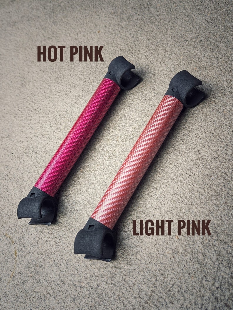 May include: Two carbon fiber rods with black end caps. The rod on the left is hot pink and the rod on the right is light pink.  "HOT PINK" and "LIGHT PINK" are written in brown text above the rods.