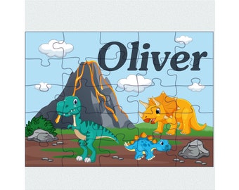May include: A personalized dinosaur puzzle featuring a green T-Rex, a yellow Triceratops, and a blue Stegosaurus. The puzzle has a volcano with orange lava and the name "Oliver" printed on it.
