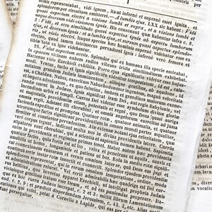 May include: Antique book pages with Latin text. The open book displays columns of small print, with visible aging and texture. The pages are yellowed, and the text is in black ink.