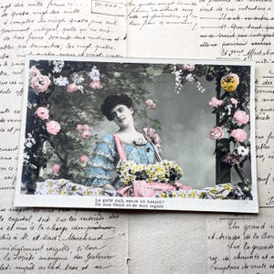 Década de 1910 - cartão postal francês de uma mulher com flores e as palavras "La gaîté nait, est-ce un hasard? De mes fleurs et de mongard"