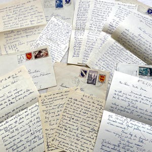 Op de afbeelding: Een verzameling vintage handgeschreven brieven en enveloppen met cursieve Franse tekst in blauwe en zwarte inkt. De verouderde papieren documenten bevatten diverse postzegels, poststempels en data uit het midden van de twintigste eeuw.
