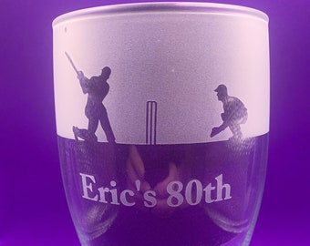 May include: A frosted glass with an etched design of two cricket players, one batting and one fielding. The glass has the text "Eric's 80th" etched on the bottom.