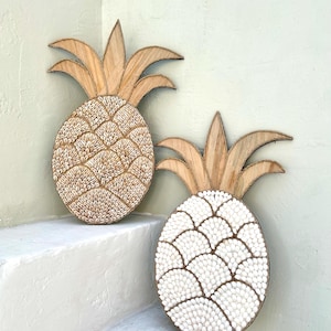 Decoración de pared bohemia con forma de piña hecha con conchas blancas
