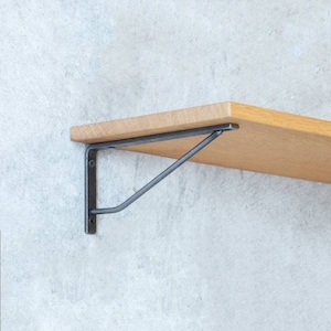 Puede incluir: Una estantería de madera con un soporte de metal negro. La estantería está montada en una pared.