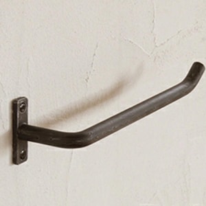 May include: A black metal toilet roll holder mounted to a wall. The holder has a simple, curved design.