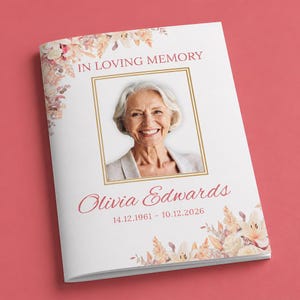 Pode incluir: Um livreto funerário branco com o retrato de uma pessoa idosa de cabelos brancos dentro de uma moldura retangular dourada. O texto diz IN LOVING MEMORY, Olivia Edwards, e as datas 14.12.1961 - 10.12.2026, acentuado por ilustrações florais.