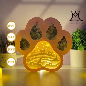 May include: A cat paw-shaped night light with a warm glow. The light features images of kittens and a silhouette of cats under a rainbow. The light has the text "SVG", "DXF", "PNG", and "PDF".