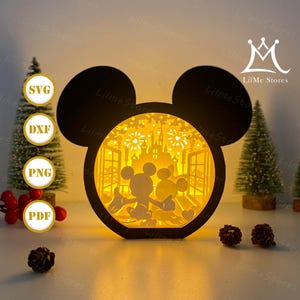 Könnte beinhalten: Eine schwarze, geschichtete Leuchtbox in Mickey Mouse-Form mit Silhouetten von Mickey und Minnie Mouse, einem Schloss und Feuerwerk. Die Box wird von einem warmen Licht beleuchtet. Der Text "SVG", "DXF", "PNG" und "PDF" ist ebenfalls enthalten.