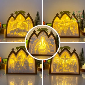 May include: Four illuminated papercraft Christmas scenes with a nativity theme. Each scene is a 3D paper cutout with a light source behind it, creating a glowing effect. The scenes depict the nativity story, including Mary, Joseph, baby Jesus, angels, and shepherds.