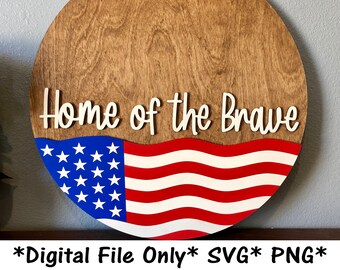 May include: A round wooden sign with the text "Home of the Brave" in white lettering. The sign is decorated with a red, white, and blue American flag.