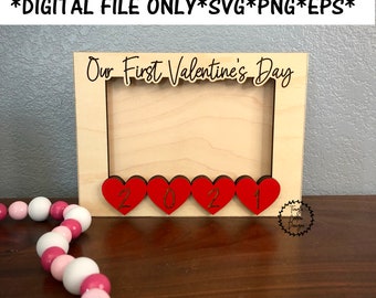 May include: A wooden picture frame with the text "Our First Valentine's Day" and the year "2021" displayed in red hearts.