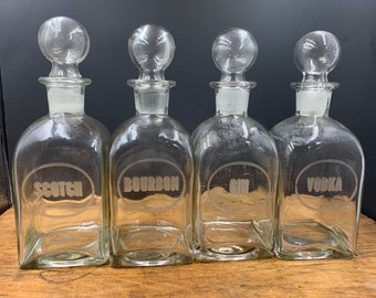 1950-1960 vintage decanter set with etched glass and glass stoppers. Boubon, Gin, Scotch and Vodka each 11” x 4” x 4” bar set