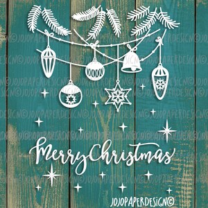 May include: White paper cut-out design of a Christmas garland with ornaments, snowflakes, and the words "Merry Christmas". The design is on a teal wood background.