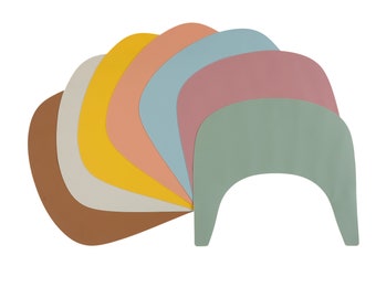 May include: A set of seven colorful, semi-circular silicone placemats in shades of brown, beige, yellow, peach, light blue, pink, and green.