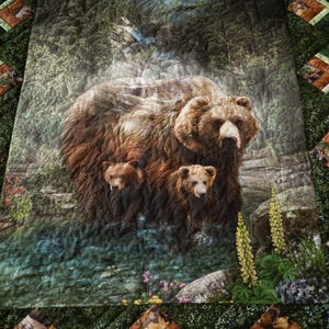 May include: A quilted blanket featuring a detailed image of a brown bear with two cubs in a forest setting. The quilt has a green border with square patches containing animal illustrations. The bear family is the focal point.