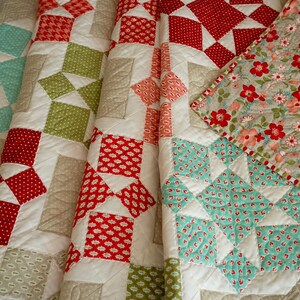 May include: A patchwork quilt with a variety of red, green, and blue patterns. The quilt is made of squares and triangles, and the fabric is a mix of cotton and linen.