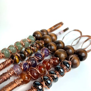 May include: Five copper wire wrapped wands with different colored gemstone beads. The wands feature green, brown, purple, orange, and black beads.