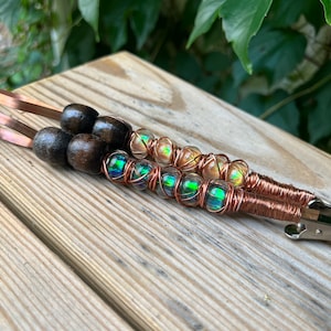 May include: Two copper wire wrapped hair clips with iridescent glass beads and brown wooden beads.