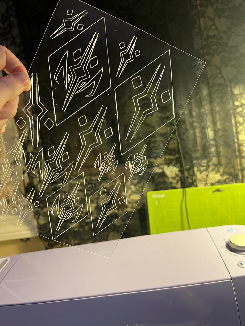 Op de afbeelding: Een doorzichtig plastic vel met een herhalend geometrisch patroon van vierkanten en driehoeken. Het patroon is in het plastic ge&euml;tst.