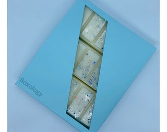 May include: A light blue box with the word "Boxology" printed on it. The box contains a white wax melt with silver glitter.