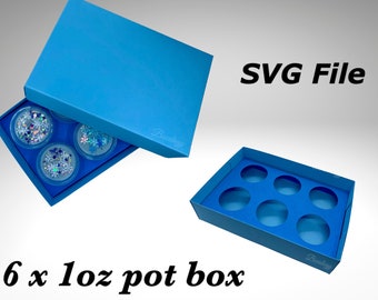 May include: A blue cardboard box with a lid, designed to hold six 1 oz pots. The box is open, revealing the interior with six circular cutouts for the pots. The text "SVG File" is visible in the upper right corner of the image.