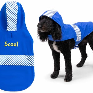 May include: Blue dog raincoat with a white and blue striped hood. The raincoat has a yellow embroidered name "Scout" on the front.