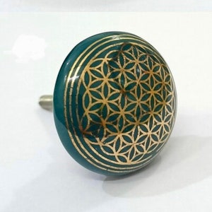 May include: Teal blue ceramic cabinet knob with a gold flower of life design.