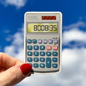 May include: A white calculator sticker with a blue and gray display. The display shows the number 8008135. The calculator has a classic design and the text "Long live the 90s" is printed on the top. The text "Twin Power Calculator" is printed on the bottom.