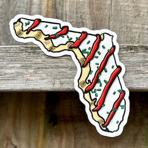 May include: A white sticker shaped like the state of Florida with red and green sprinkles on top.