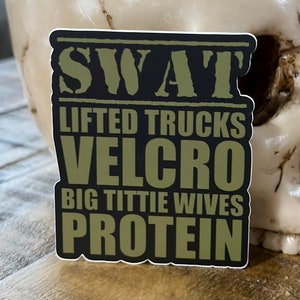 May include: A black and green sticker with the text "SWAT" in large white letters. The text "LIFTED TRUCKS", "VELCRO", "BIG TITTIE WIVES", and "PROTEIN" is written in smaller white letters.