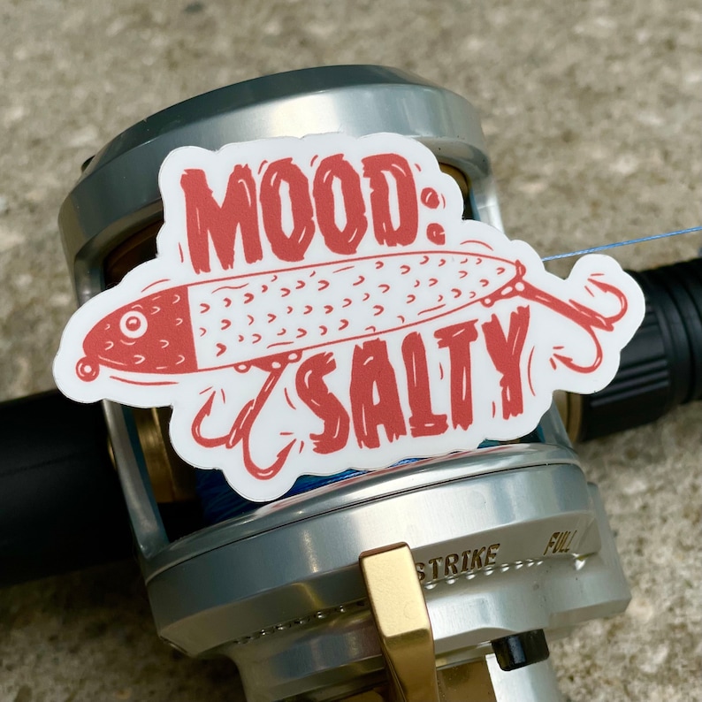 以下が含まれることがあります： 赤い釣りルアーと「MOOD: SALTY」という赤い文字が書かれた白いステッカーです。