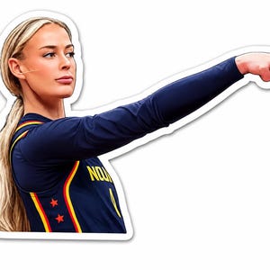 May include: A die-cut sticker featuring a blonde person with a ponytail, wearing a dark blue long-sleeve athletic jersey with yellow and red accents, including two red stars and the partial yellow text "NOU" visible, pointing with their right hand.