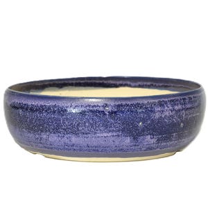 Peut inclure: Un bol rond en céramique à profil bas. L'extérieur est indigo avec une texture mouchetée et l'intérieur est de couleur crème. Le bol a un large bord et un design simple, adapté à diverses utilisations.