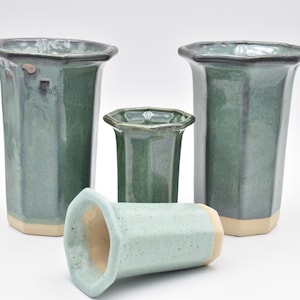 Peut inclure: Quatre vases en céramique verte de tailles différentes avec des formes octogonales. Les vases ont un glacis vert clair avec une finition mouchetée.