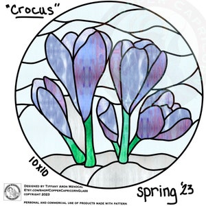 May include: A stained glass design of purple crocuses with green stems on a white background. The design is in a circle and has the text "Crocus" at the top and "Spring '23" at the bottom.