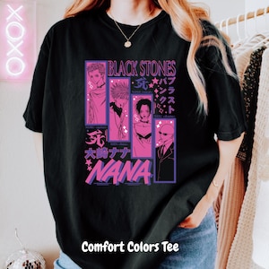 May include: Black Comfort Colors tee featuring a graphic design with the text "BLACK STONES" and "NANA" in pink and purple. The design includes illustrations of anime characters. The text "Comfort Colors Tee" is at the bottom.