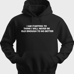 以下が含まれることがあります： 「I AM STARTING TO THINK I WILL NEVER BE OLD ENOUGH TO NO BETTER」という白文字がプリントされた黒いパーカー。フロントポケットとドローストリング付きフードが付いています。カジュアルなスタイル。