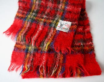 May include: Red, green, blue, and yellow plaid scarf with frayed edges. The scarf has a white tag with the text "All Mohair Pile Hand Knit Made in Scotland".