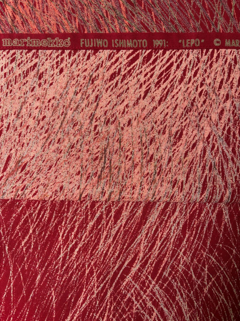 May include: Red fabric with a white, scribbled pattern. The top section is a lighter shade of red. The text "marimekko FUJIWO ISHIMOTO 1991: "LEPO"" is printed across the top in a red band.
