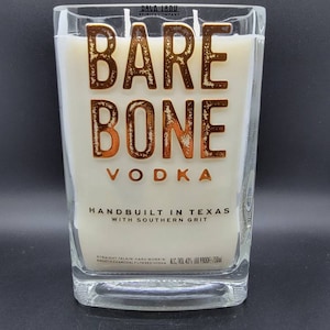 May include: A clear glass bottle of Bare Bone Vodka, a hand-crafted spirit from Texas. The label features the brand name in gold lettering with a rustic texture, along with the tagline "Handbuilt in Texas with Southern Grit". The bottle is 750ml and has an alcohol content of 40% (80 proof).