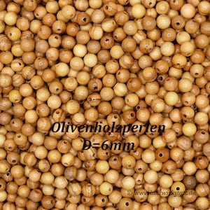 May include: A close-up image of a pile of natural wood beads. The beads are round and have a light brown color. The beads are 6 mm in diameter. The text "Olivenholzperlen D=6mm" is visible in the image.