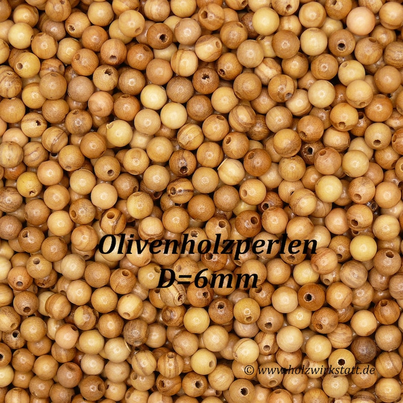 May include: A close-up image of a pile of natural wood beads. The beads are round and have a light brown color. The beads are 6 mm in diameter. The text "Olivenholzperlen D=6mm" is visible in the image.